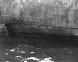 Torpedo hole in starboard side, before the ship had been lightened and temporary repairs made. (<em>National Archives Photo</em>)